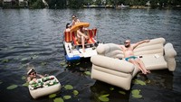Seorang pria berjemur di perahu karet berbentuk sofa di sungai Spree, Berlin, Jerman. Getty Images/Steffi Loos  
