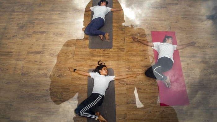 The photographer and clouds are reflected on a glass roof as Indian women perform yoga to mark International Yoga Day on the top of a building in Gauhati, India, Monday, June 21, 2021. (AP Photo/Anupam Nath)