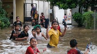 Anak-anak di sekitar asyik bermain kala lokasi terendam banjir.