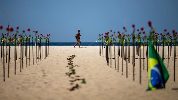 RIO DE JANEIRO, BRAZIL - JUNE 20: A woman shows a banner during an event to pay homage to the over 500,000 registered victims of coronavirus and protest against the government's response to the pandemic organized by ONG Rio de Paz at Copacabana Beach on June 20, 2021 in Rio de Janeiro, Brazil. The death toll in Brazil surpassed 500,000 people on Saturday June 19. Brazilian President Jair Bolsonaro, who initially downplayed the virus, undergoes a Congress probe on his government's mismanagement of the pandemic. (Photo by Buda Mendes/Getty Images)