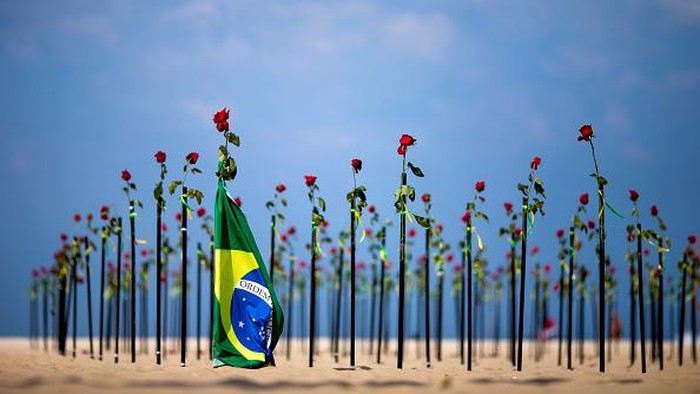 RIO DE JANEIRO, BRAZIL - JUNE 20: A woman shows a banner during an event to pay homage to the over 500,000 registered victims of coronavirus and protest against the governments response to the pandemic organized by ONG Rio de Paz at Copacabana Beach on June 20, 2021 in Rio de Janeiro, Brazil. The death toll in Brazil surpassed 500,000 people on Saturday June 19. Brazilian President Jair Bolsonaro, who initially downplayed the virus, undergoes a Congress probe on his governments mismanagement of the pandemic. (Photo by Buda Mendes/Getty Images)