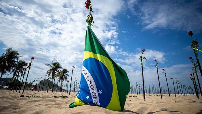 RIO DE JANEIRO, BRAZIL - JUNE 20: A woman shows a banner during an event to pay homage to the over 500,000 registered victims of coronavirus and protest against the governments response to the pandemic organized by ONG Rio de Paz at Copacabana Beach on June 20, 2021 in Rio de Janeiro, Brazil. The death toll in Brazil surpassed 500,000 people on Saturday June 19. Brazilian President Jair Bolsonaro, who initially downplayed the virus, undergoes a Congress probe on his governments mismanagement of the pandemic. (Photo by Buda Mendes/Getty Images)