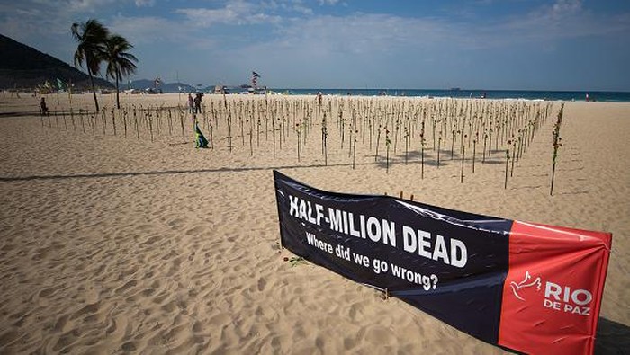 RIO DE JANEIRO, BRAZIL - JUNE 20: A woman shows a banner during an event to pay homage to the over 500,000 registered victims of coronavirus and protest against the government's response to the pandemic organized by ONG Rio de Paz at Copacabana Beach on June 20, 2021 in Rio de Janeiro, Brazil. The death toll in Brazil surpassed 500,000 people on Saturday June 19. Brazilian President Jair Bolsonaro, who initially downplayed the virus, undergoes a Congress probe on his government's mismanagement of the pandemic. (Photo by Buda Mendes/Getty Images)