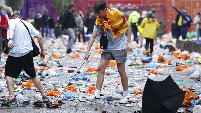 Scotland fans helps clean up after fans gathered in Leicester Square prior to the Euro 2020 soccer championship group D match between England and Scotland, in London, Friday, June 18, 2021. (Kirsty O'Connor/PA via AP)