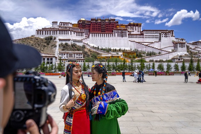 A Chinese tourist gets ready to pose for a photo atop a white yak being led by a Tibetan man in Namtso in western Chinas Tibet Autonomous Region, Wednesday, June 2, 2021. Tourism is booming in Tibet as more Chinese travel in-country because of the coronavirus pandemic, posing risks to the regions fragile environment and historic sites. (AP Photo/Mark Schiefelbein)