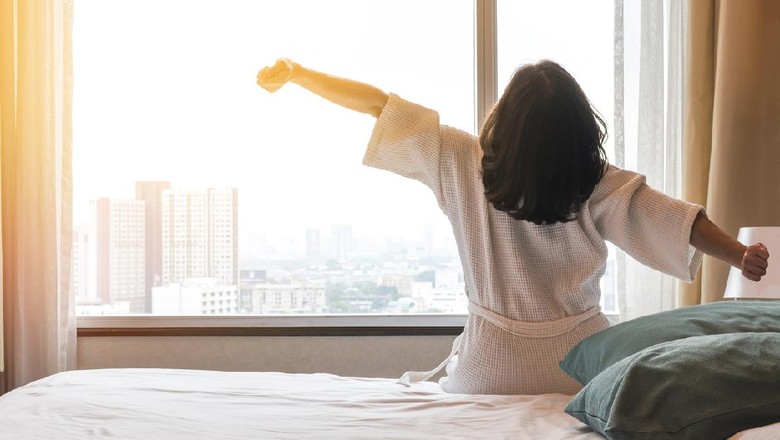Simple city lifestyle happy woman waking up in the morning taking some rest relaxing in luxury comfy city hotel room