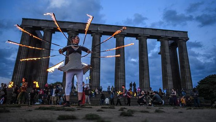 Aksi Warga Inggris Rayakan Titik Balik Matahari EDINBURGH, SCOTLAND - JUNE 21: Performers from Fire Club Edinburgh mark the summer solstice during a fire festival on Calton Hill on June 21, 2021 in Edinburgh, United Kingdom. The summer solstice is the longest day in the northern hemisphere and has inspired a range of folkloric traditions across Europe. (Photo by Peter Summers/Getty Images)
