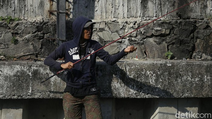 Sejumlah warga tampak memancing di bantaran kali di kawasan Cempaka Putih, Jakarta Timur, Selasa (22/6/2021).