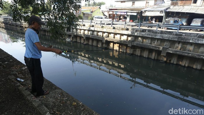 Sejumlah warga tampak memancing di bantaran kali di kawasan Cempaka Putih, Jakarta Timur, Selasa (22/6/2021).