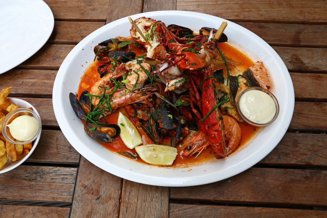 Close up large grilled seafood platter on wooden table, high angle view
