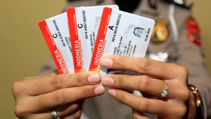 Petugas menunjukkan Surat Izin Mengemudi (SIM) seusai proses pembuatan di Kantor Satuan Penyelenggara Administrasi SIM (Satpas SIM) Polresta Banda Aceh, Aceh, Selasa (22/6/2021). Kepolisian Polda Aceh menyatakan pengurusan Surat Izin Mengemudi (SIM) dan Surat Keterangan Catatan Kepolisian (SKCK) tidak perlu menyertakan surat keterangan dan sertifikat vaksin COVID-19. ANTARA FOTO/Syifa Yulinnas/hp.
