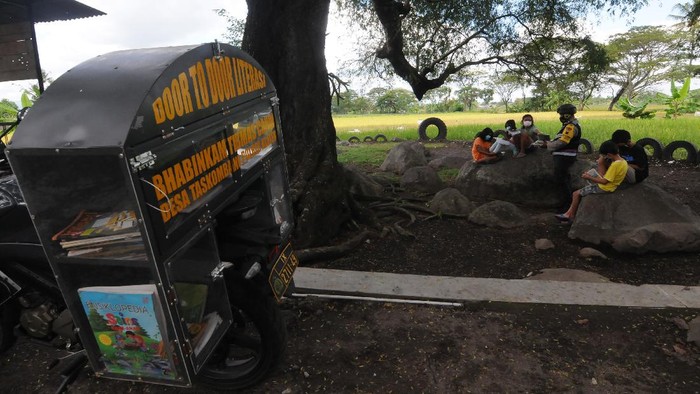 Sejumlah anak antre saat mengembalikan buku perpustakaan keliling Bhabinkamtibmas Polres Klaten di Taskombang, Manisrenggo, Klaten, Jawa Tengah, Selasa (22/6/2021). Aiptu Setyo Widyantoro mengubah motor dinasnya menjadi fasilitas perpustakaan keliling sebagai cara untuk meningkatkan daya minat baca dan memanfaatkan waktu luang anak saat masa pandemi COVID-19. ANTARA FOTO/Aloysius Jarot Nugroho/foc.
