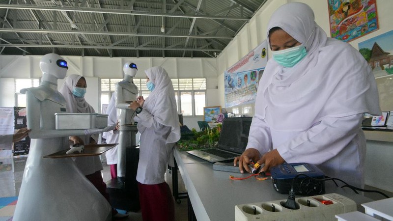 Seorang santri mengoperasikan robot Sabai menggunakan remote di kafe Arfa, Perguruan Diniyyah Putri Padangpanjang, Sumatera Barat.