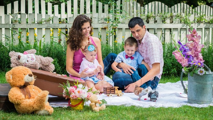 Young couple sitting in the lawn with the children and are about to kiss in Lviv, Ukraine.