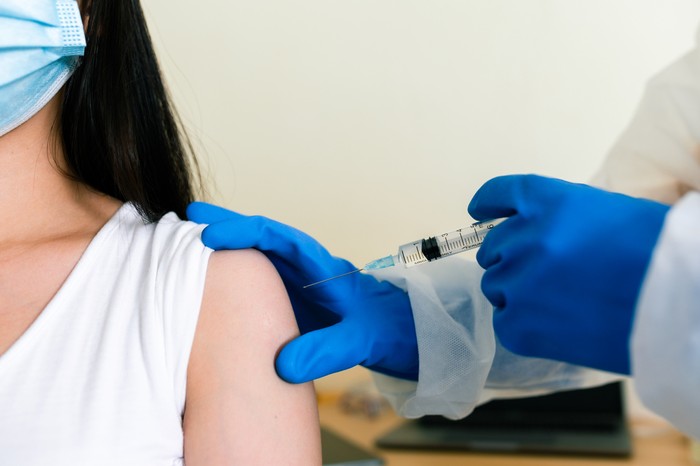 Ilustrasi vaksin Doctors wearing PPE uniforms white gloves are inoculating the arm muscles to prevent COVID 19.