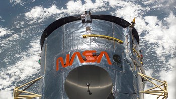 Foto ini, diambil selama Service Mission 3B, menunjukkan salah satu dari dua antena gain tinggi Hubble (piringan hitam di dekat pusat) dalam posisi disimpan sementara teleskop ditambatkan di ruang kargo pesawat ulang-alik. Salah satu antena low-gain berbentuk kerucut juga dapat dilihat di kanan atas. Foto: NASA