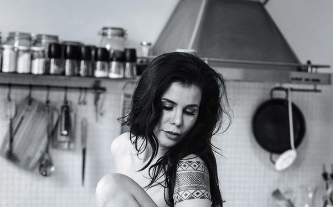 Seperti dalam foto bertema hitam putih ini. Tanpa mengenakan busana, Candida berpose di atas meja kayu di dapurnya. Foto: dok. Instagram