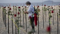 Seorang wanita meletakkan mawar untuk menghormati 500.000 kematian akibat virus corona di pantai Copacabana, Rio de Janeiro, (20/6/2021). AP/Silvia Izquierdo