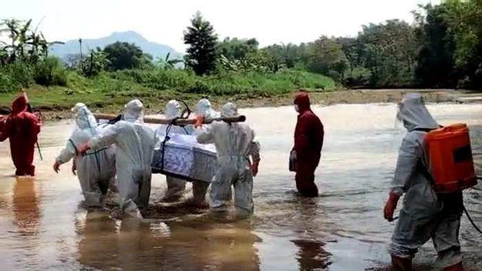 Video pemakaman diduga pasien COVID-19 di Kabupaten Wonogiri, Jawa Tengah, ramai diperbincangkan. Dalam video tersebut, tampak petugas berpakaian APD lengkap harus menyeberangi sungai, melewati pematang sawah hingga berjalan sejauh satu kilometer untuk memakamkan pasien positif COVID-19.
