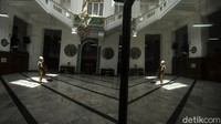 Seorang pengurus Masjid membersihkan lantai masjid.