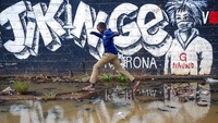 Anak kecil menghindari genangan di depan mural dalam bahasa Swahili yang berarti Lindungi Keluarga dan Dapatkan Vaksin Corona di Nairobi, Kenya (12/6). Afrika dengan jumlah populasi 18 persen dari penduduk dunia hanya menerima sekitar 2 persen dosis vaksin global. AP Photo/Brian Inganga