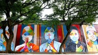 Pejalan kaki melintas di depan mural karya seniman Brazil, Eduardo Kobra di Sao Paolo, (22/5/2020). Mario Tama/Getty Images