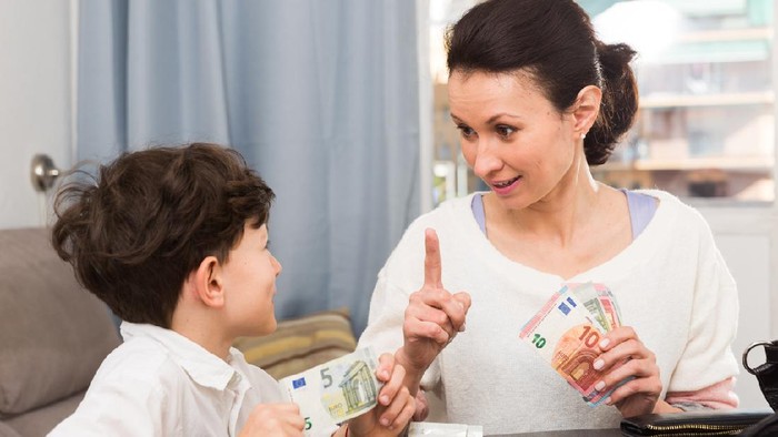 Children and money concept. Woman admonishing teen boy while giving him money at home