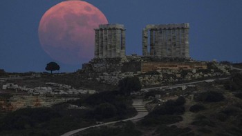 Strawberry full moon terlihat di candi Poseidon, sekitar 70 kilometer di selatan Athena. Ini adalah kemunculan supermoon terakhir di tahun 2021. Foto: Associated Press