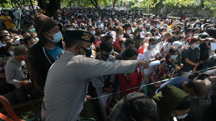 ANTREAN VAKSINASI COVID-19 MASSAL DI BALI Anggota Polisi mengarahkan ribuan warga yang antre vaksinasi COVID-19 massal di Denpasar, Bali, Sabtu (26/6/2021). Petugas Kepolisian berupaya menertibkan masyarakat yang membludak saat mengikuti vaksinasi massal yang digelar di ruang publik tersebut untuk mencegah kerumunan dan agar tetap menerapkan protokol kesehatan COVID-19. ANTARA FOTO/Nyoman Hendra Wibowo/rwa.
