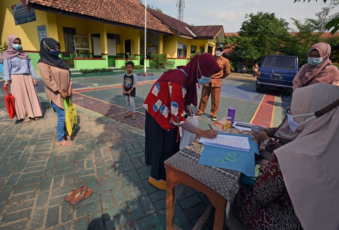 Sejumlah wali murid antre untuk mendaftarkan anaknya secara offline atau luar jaringan (Luring) ke sekolah SD Negeri Sepang di Kecamatan Taktakan, Serang, Banten, Selasa (22/6/2021). Untuk mencegah penyebaran COVID-19 Pemda setempat mewajibkan penerapan protokol kesehatan secara ketat dalam penerimaan peserta didik baru (PPDB) dengan membuat daftar antrian pendaftar hanya 20 orang per hari serta memperpanjang waktu penerimaan siswa hingga akhir Juni 2021. ANTARA FOTO/Asep Fathulrahman/hp.