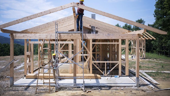 Builders working on wooden construction site, modern wooden house.