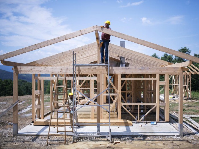 Builders working on wooden construction site, modern wooden house.