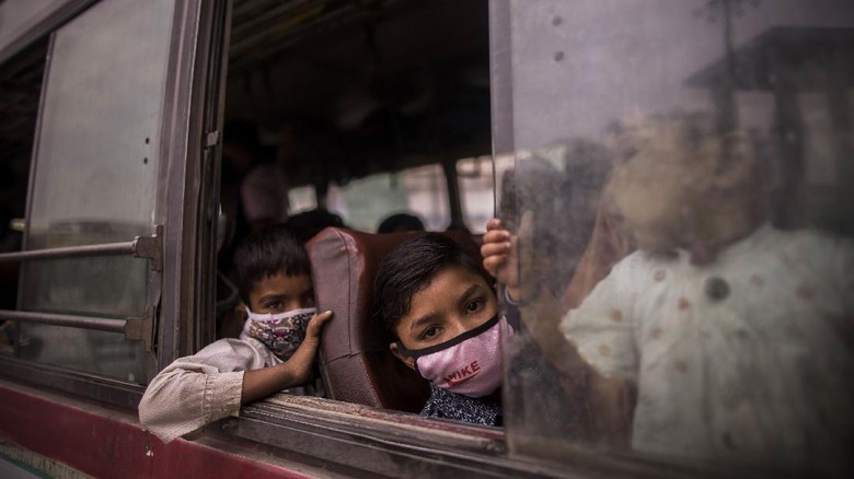 NEW DELHI, INDIA - APRIL 20: Children of migrant labourers working in Delhi look out the window of a bus as they head to their native villages after the Delhi government imposed a week long lockdown to battle the deadlier second wave of the Covid-19 coronavirus infections on on April 20, 2021 in New Delhi, India. Covid-19 cases are spiralling out of control in India, with daily infections approaching 300,000, according to health ministry data, bringing the nationwide tally of infections to almost 14 million. The latest wave has already overwhelmed hospitals and crematoriums. (Photo by Anindito Mukherjee/Getty Images)