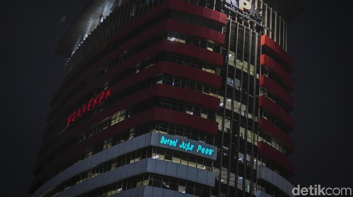 Pedagang menyaksikan proyeksi bertuliskan #mositidakpercaya saat aksi oleh aktivis Greenpeace di Gedung Merah Putih KPK, Jakarta, Senin (28/6/2021). Aksi tersebut menyuarakan keadilan bagi 51 pegawai KPK yang dinonaktifkan akibat dinyatakan tidak lulus Tes Wawasan Kebangsaan, juga menyampaikan pesan untuk menyelamatkan lembaga anti korupsi dari cengkraman oligarki. ANTARA FOTO/Galih Pradipta/foc.