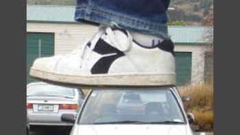 Kaki raksasa dengan sepatu ketsnya akan menginjak atap mobil yang tengah parkir. Foto: dok illumeably