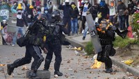 Polisi yang terkena bom bensin berusaha menyelamatkan diri.