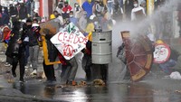 Massa menghalau tembakan water canon menggunakan perkakas yang ditemui di jalanan.