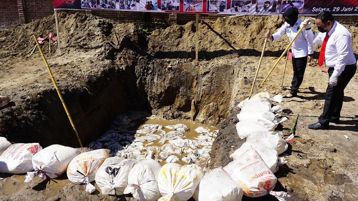 Anggota Polri menjaga karung dan plastik berisi minuman keras jenis captikus pada pemusnahan barang bukti hasil sitaan di Polres Gorontalo Kota, Kota Gorontalo, Gorontalo, Selasa (29/6/2021). Satnarkoba Polres Gorontalo Kota memusnahkan 4.600 liter captikus hasil sitaan pada bulan Mei 2021 sebagai salah satu upaya pemberantasan peredaran minuman keras di wilayah itu. ANTARA FOTO/Adiwinata Solihin/nz