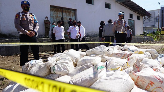 Anggota Polri menjaga karung dan plastik berisi minuman keras jenis captikus pada pemusnahan barang bukti hasil sitaan di Polres Gorontalo Kota, Kota Gorontalo, Gorontalo, Selasa (29/6/2021). Satnarkoba Polres Gorontalo Kota memusnahkan 4.600 liter captikus hasil sitaan pada bulan Mei 2021 sebagai salah satu upaya pemberantasan peredaran minuman keras di wilayah itu. ANTARA FOTO/Adiwinata Solihin/nz