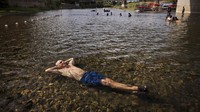 Seorang warga California berendam di sungai dangkal yang melintas di Veterans Memorial Beach, AS, (16/6/2021). Kent Porter/The Press Democrat via AP.