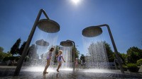 Anak-anak bermain air di tengah cuaca panas di taman kota  Vilnius, Lithuania (19/6/2021). Gelombang panas menerpa Lithuania dengan suhu mencapai 32 derajat Celcius. AP Photo/Mindaugas Kulbis.