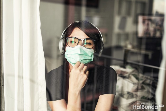 Portrait of young woman in the her apartment wearing face protective mask to prevent Coronavirus