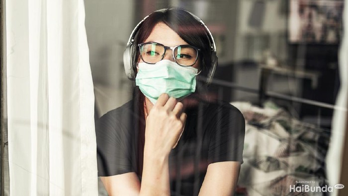 Portrait of young woman in the her apartment wearing face protective mask to prevent Coronavirus
