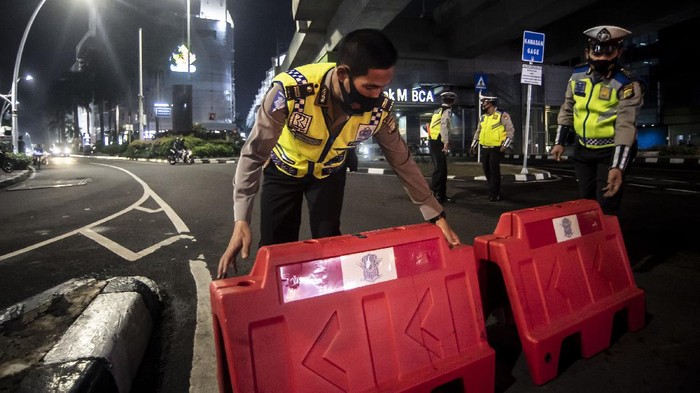 Petugas kepolisian menyusun pembatas jalan saat akan melakukan penutupan jalan dalam rangka pembatasan mobilitas warga guna menekan penyebaran COVID-19 di kawasan Bulungan, Jakarta, Senin (21/6/2021). Pembatasan tersebut dilakukan mulai pukul 21.00 WIB hingga 04.00 WIB di 10 titik di Kota Jakarta  diantaranya Jalan Cikini Raya, kawasan Jalan Sabang, kawasan BKT, kawasan Kemang, PIK 2, kawasan Kota Tua dan Bulungan. ANTARA FOTO/Muhammad Adimaja/wsj.
