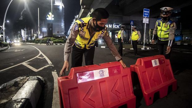 Petugas kepolisian menyusun pembatas jalan saat akan melakukan penutupan jalan dalam rangka pembatasan mobilitas warga guna menekan penyebaran COVID-19 di kawasan Bulungan, Jakarta, Senin (21/6/2021). Pembatasan tersebut dilakukan mulai pukul 21.00 WIB hingga 04.00 WIB di 10 titik di Kota Jakarta diantaranya Jalan Cikini Raya, kawasan Jalan Sabang, kawasan BKT, kawasan Kemang, PIK 2, kawasan Kota Tua dan Bulungan. ANTARA FOTO/Muhammad Adimaja/wsj.