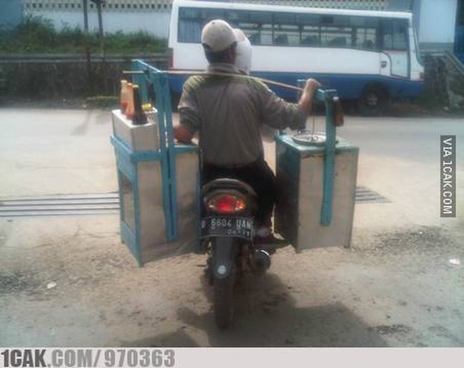 Berkat kemajuan teknologi, pedagang yang satu ini nggak perlu lagi keliling dengan jalan kaki. Biar nggak capai, mending pakai motor aja. Ide bagus bukan? Foto: 1cak.com