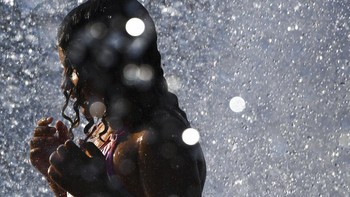 Seorang anak di Washington mendinginkan diri di air mancur kota itu. Temperatur udara memang sangat tinggi, bahkan memecahkan rekor. Foto: AP