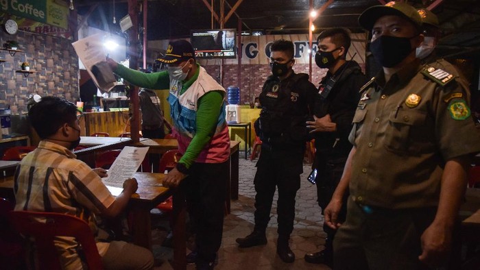 Petugas gabungan dari Kepolisian dan Satpol PP meminta pengunjung dan pemilik usaha kuliner yang melewati batas aturan waktu operasional untuk membubarkan diri saat sidak penerapan Pemberlakuan Pembatasan Kegiatan Masyarakat (PPKM) Mikro di Medan, Sumatera Utara, Jumat (30/6/2021) malam. Tim Patroli Protokol Kesehatan dan PPKM Mikro menyegel warung makan tersebut akibat melanggar Surat Edaran (SE) Wali Kota Medan Bobby Nasution. ANTARA FOTO/Fransisco Carolio/Lmo/wsj.