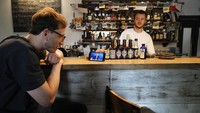 Bartender melihat siaran live streaming yang menampilkan nara sumber talkshow Presiden Vladimir Putin, di Moskow (30/6/2021).  Penting untuk mendengarkan, bukan pada orang-orang yang hanya sedikit memahami tentang hal ini dan menyebarkan desas-desus, tetapi kepada para spesialis, kata Putin. AP Photo/Pavel Golovkin