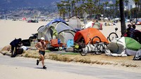Warga yang sedang berolahraga melewati deretan pemukiman kumuh di Venice Beach, Los Angeles (8/6). Para gelandangan dan pemukiman kumuh dari tenda bakal digusur pada 1 Juli waktu setempat atau 4 hari sebelum perayaan kemerdekaan AS. AP Photo/Marcio Jose Sanchez.